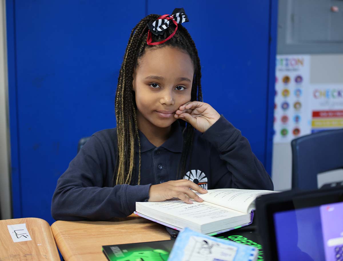 Elementary student smiling and posing together in a classroom.